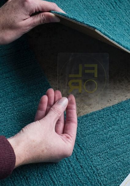 Hands of a person using a FLORdot to assemble a FLOR area rug from carpet tiles.
