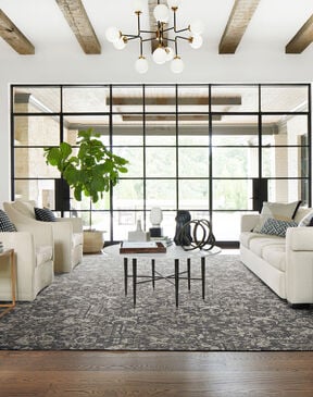 Grand living room with wood beams and wall of windows featuring FLOR Fancy Free area rug shown in Pigeon
