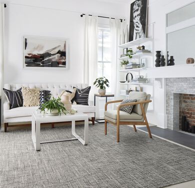 Living room with coffee table and accent chair on top of FLORs London Twill shown in Flint/Pearl