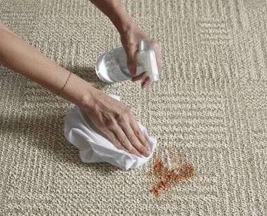 Hands of a person cleaning a spill on a FLOR carpet tile.