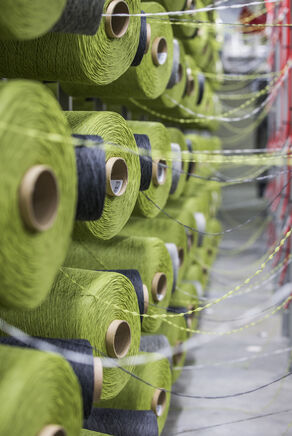 Close view of industrial skeins of green, gray, and white carpet tile threads.