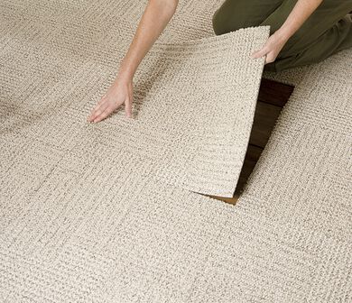 Single FLOR carpet tile being removed from installed FLOR area rug.