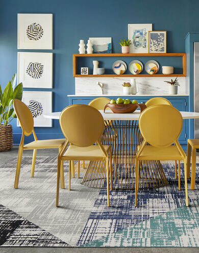 FLOR Dappled Daylight area rug in Black, Pigeon, Titanium, Marigold, Cobalt, and Teal, yellow chairs, and a metal dining table. 