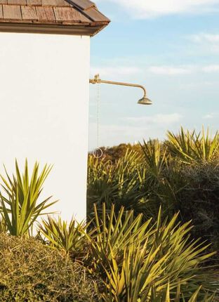 Photo of an outdoor showerhead on the beach with sunset lighting up beach grass