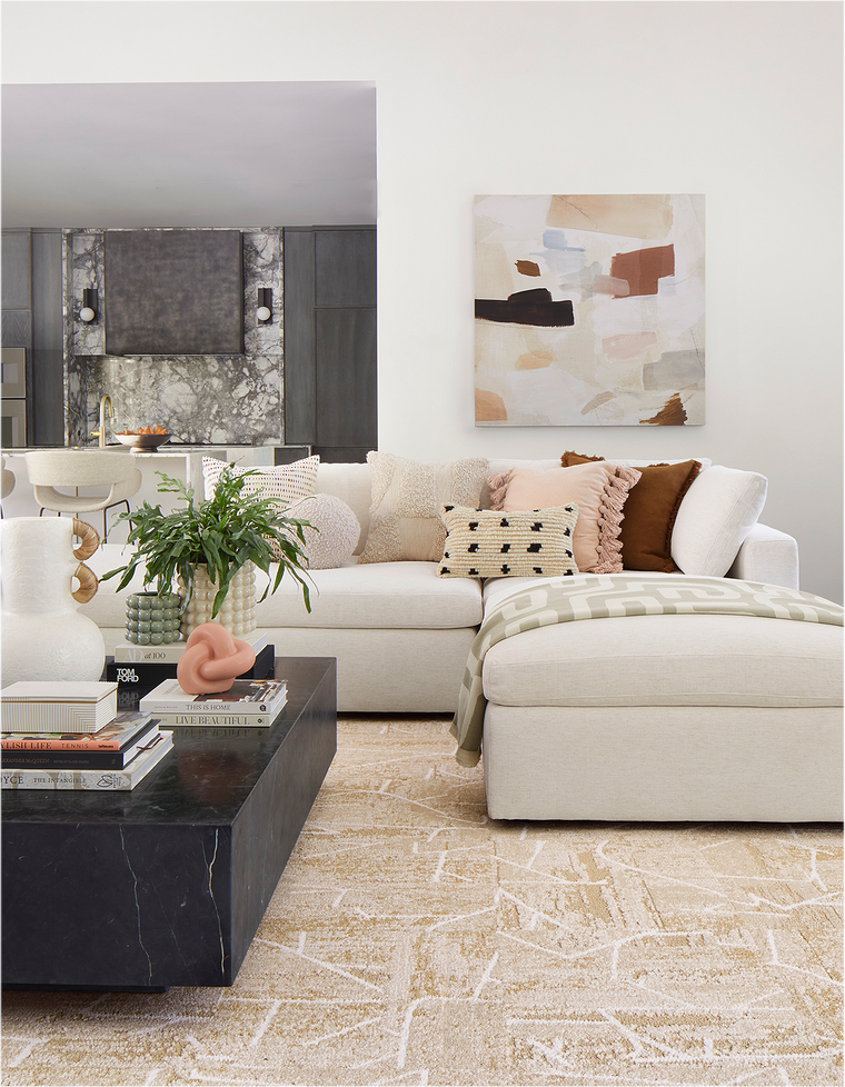 Living room with a tan couch, FLOR terrain area rug shown in pearl, and black stone coffee table