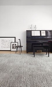It's Snow Problem area rug in Frost, shown with a black piano and black and white art.