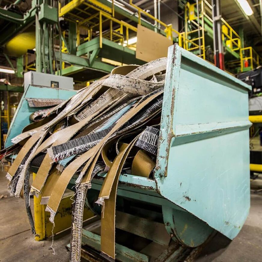 FLOR carpet tiles being recycled in a light blue machine. 