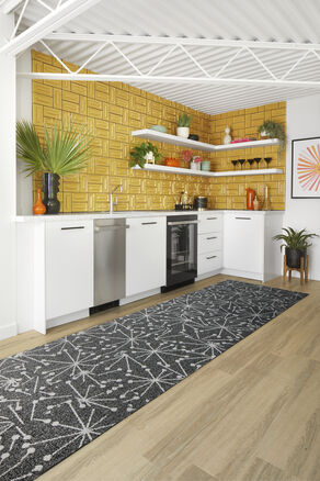 Kitchen with gold backsplash featuring FLOR Mod Cafe runner rug shown in Black