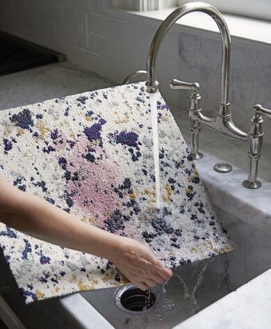 Person rinsing Painter's Palette FLOR carpet tile stained with red wine in the sink. 