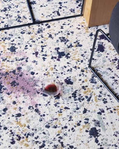 Close view of a spilled glass of red wine on Painter's Palette carpet tiles.. 