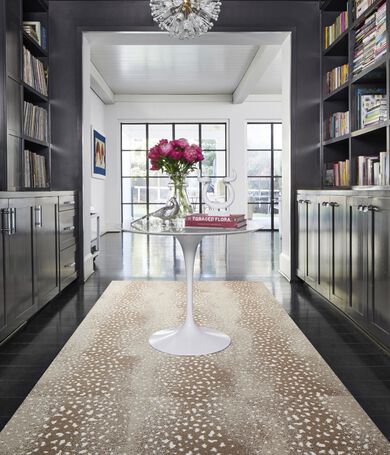 Glossy black built in bookshelf frames a contemporary entryway featuring FLOR Doe Re Mi area rug shown in Pebble