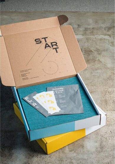 Open box reading "START" showing FLOR carpet tiles, FLORdots, and installation instructions.