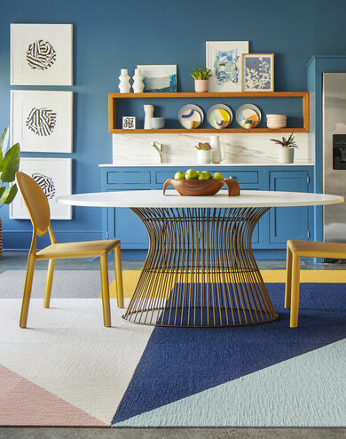 FLOR Made You Look area rug in Blush, Bone, Grey, Marigold, Indigo, and Seafoam, yellow chairs, and a metal dining table. 