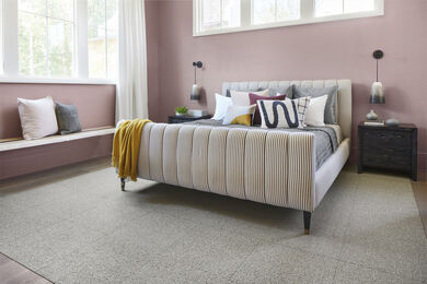 Bedroom with mauve walls, purple and mustard decor with FLOR Heaven Sent area rug shown in Pigeon