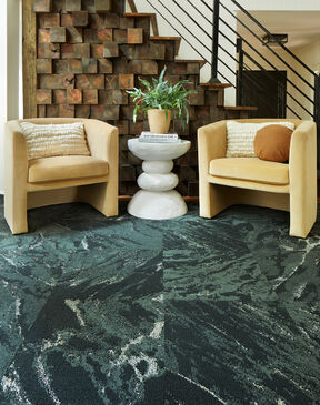 Seating area next to wooden staircase featuring FLOR area rug Zera shown in Pine.