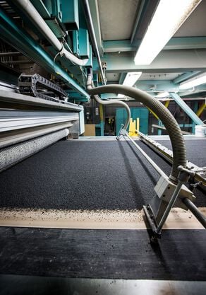 Worker in the FLOR production facility scanning a sheet of tufted yarn