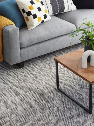 Couch with FLOR Open Invitation area rug shown in Grey