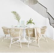 Beachy dining room with white and wicker chairs on a rug of Pleats And Thanks in Beige.