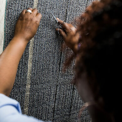 FLOR employee inspecting carpet fibers while holding scissors