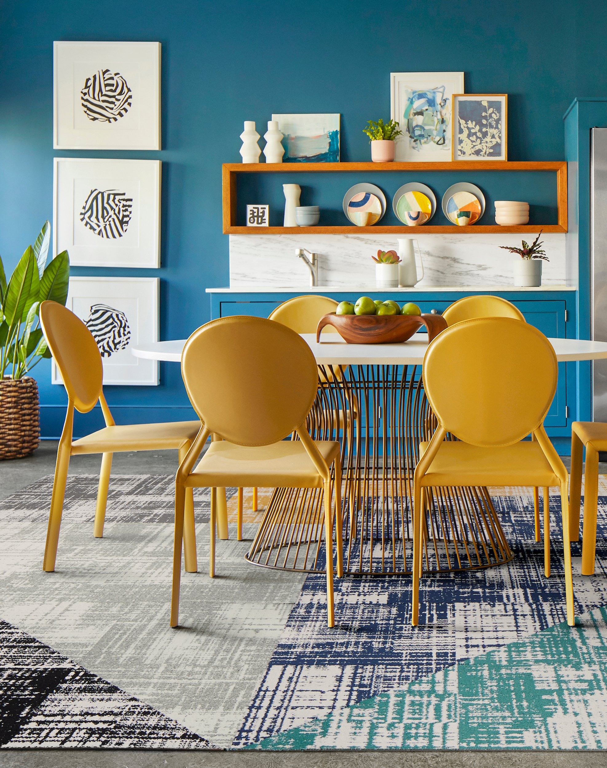 FLOR Dappled Daylight area rug in Black, Pigeon, Titanium, Marigold, Cobalt, and Teal, yellow chairs, and a metal dining table. 